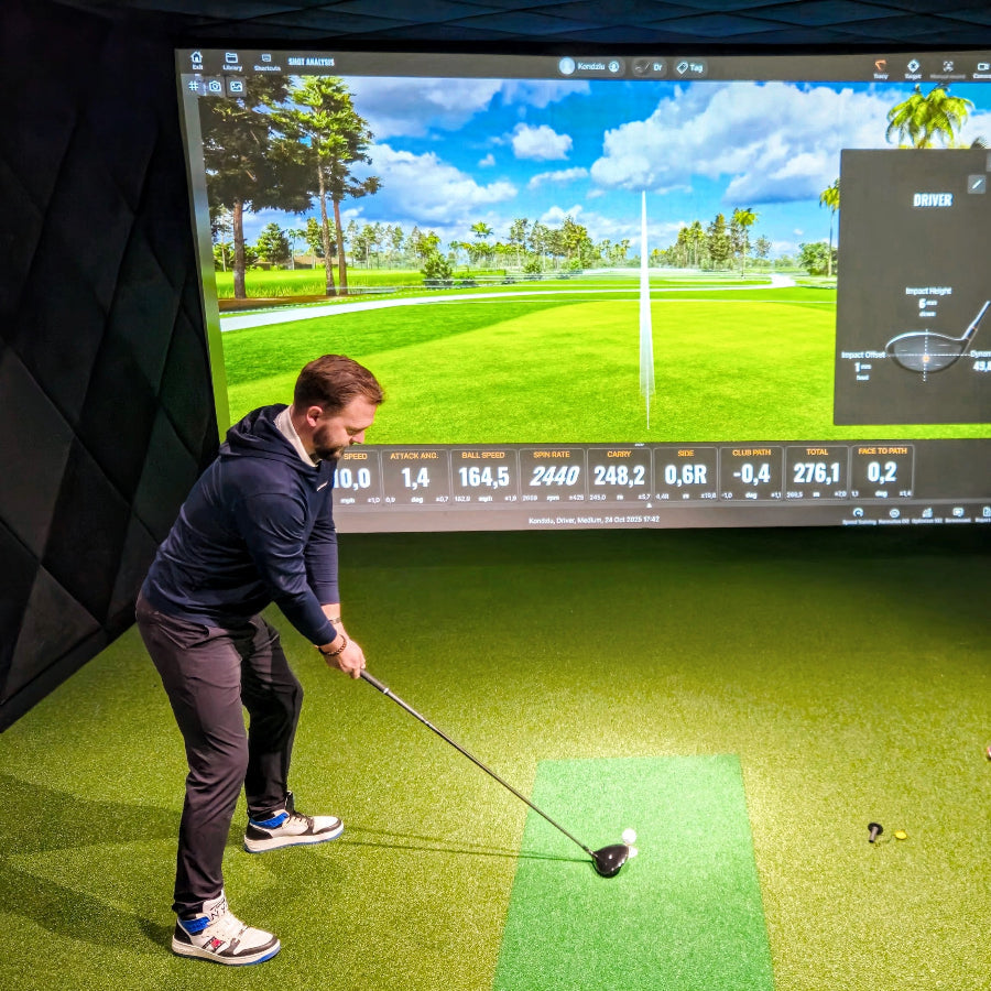 Golfista na symulatorze golfowym SIM|GOLF – obraz z projektora na ekranie impaktowym